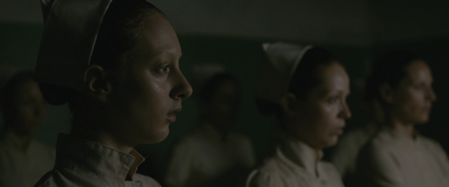 Midwives in profile, lit from the side in the dark